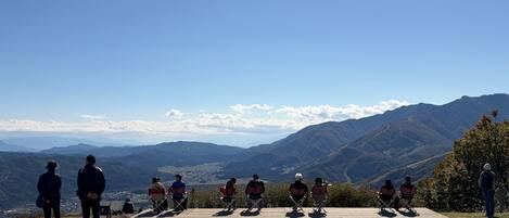 A group of people seated on a wooden platform with a scenic mountain view in the background.