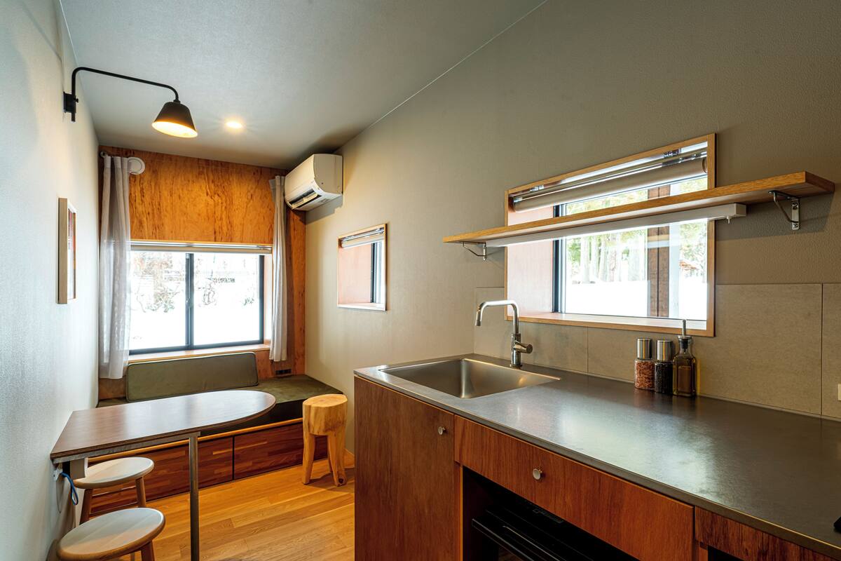 Cocina compacta con encimera de madera, lavaplatos integrado y ventana que proporciona luz natural.