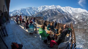 A snow-covered outdoor seating area with tables and chairs, overlooking snow-capped mountains. - B&D HAKUBA IWATAKE (Hakuba)