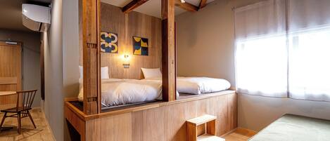 Een kleine kamer met een houten bed, een bureau en een stoel.