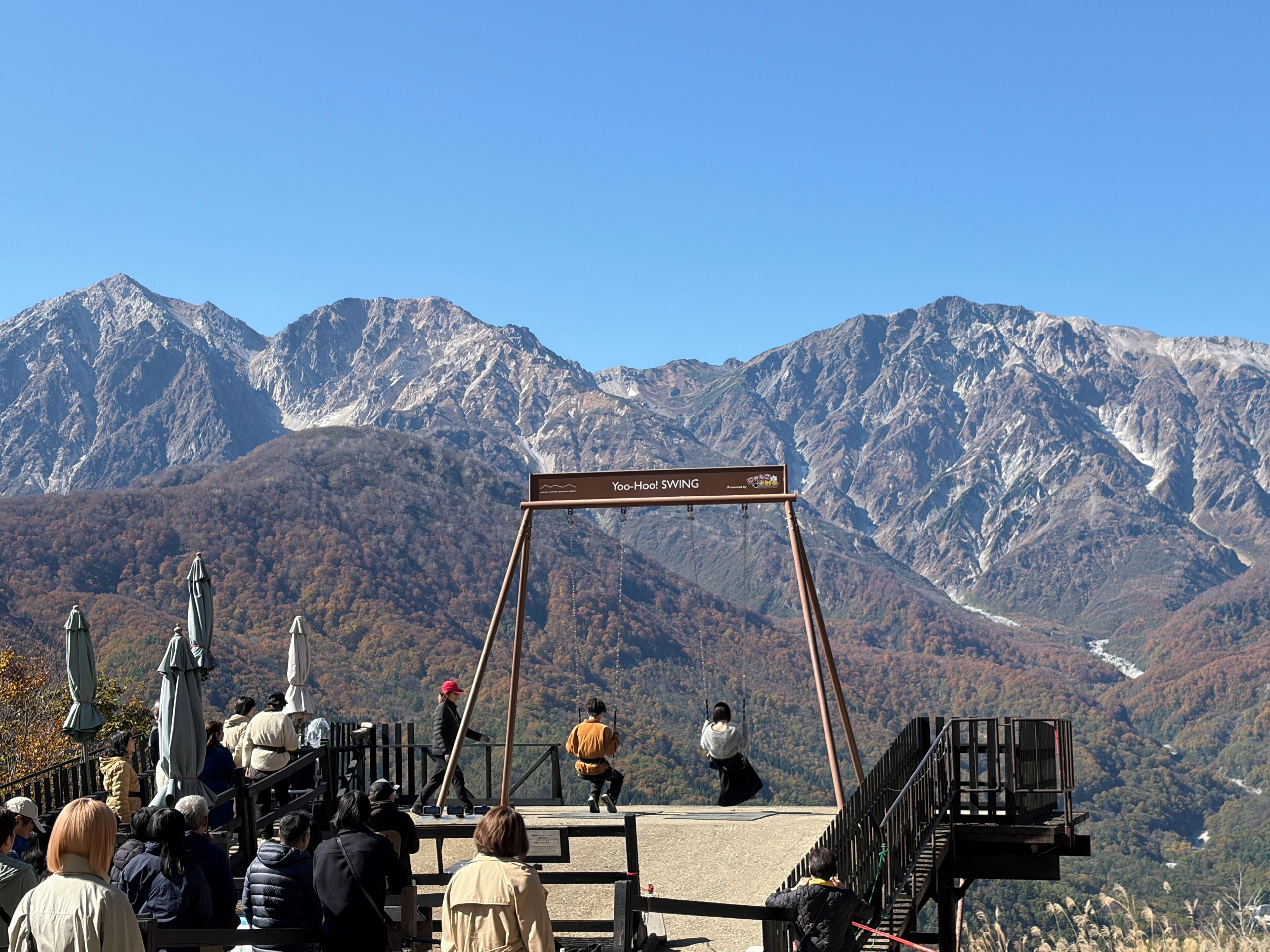 A mountain view with a swing set labeled 'Yoo-Hoo! SWING' and a wooden staircase leading up to it.