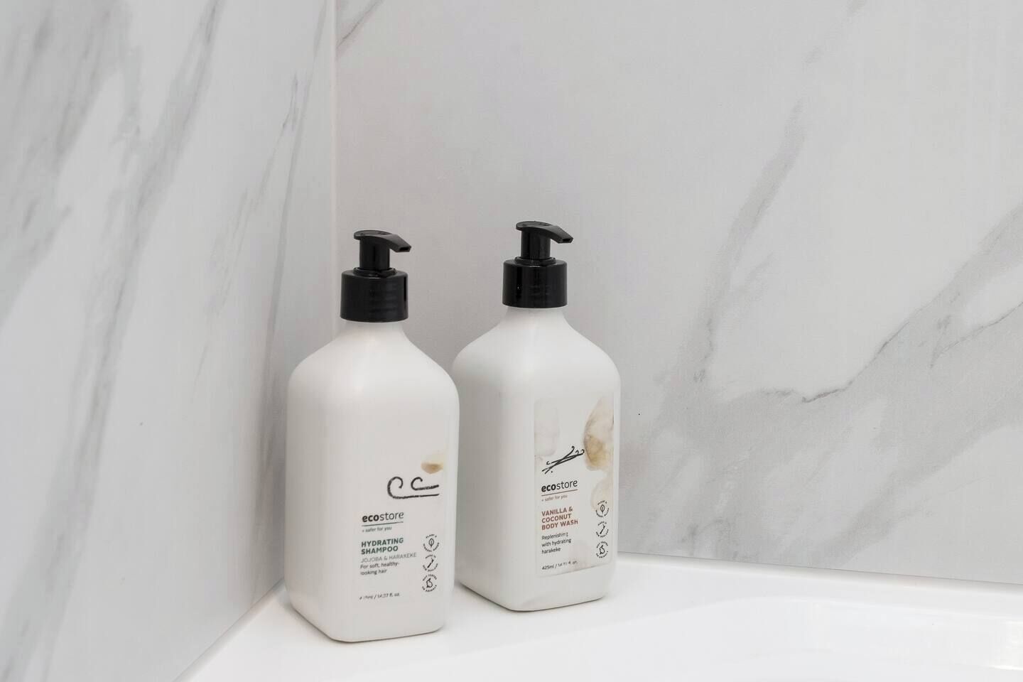 Due flaconi di shampoo e bagnoschiuma su una superficie in marmo.