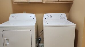 Dos lavadoras de carga frontal en un cuarto de lavado con gabinetes de madera arriba.