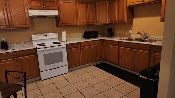 Una cocina con armarios de madera, estufa blanca, microondas y cafetera.