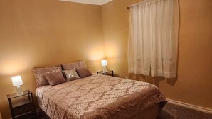 Un dormitorio con una cama grande, dos mesitas de noche y una ventana con cortinas.