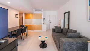 A modern living room with a sofa, a dining table with chairs, a TV, and a small coffee table. - Tyms Xujiahui Elegant 1BR APT  (Shanghai)