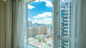A view from a window with curtains, overlooking a cityscape with high-rise buildings and a clear sky. - Tyms Xujiahui Elegant 1BR APT  (Shanghai)