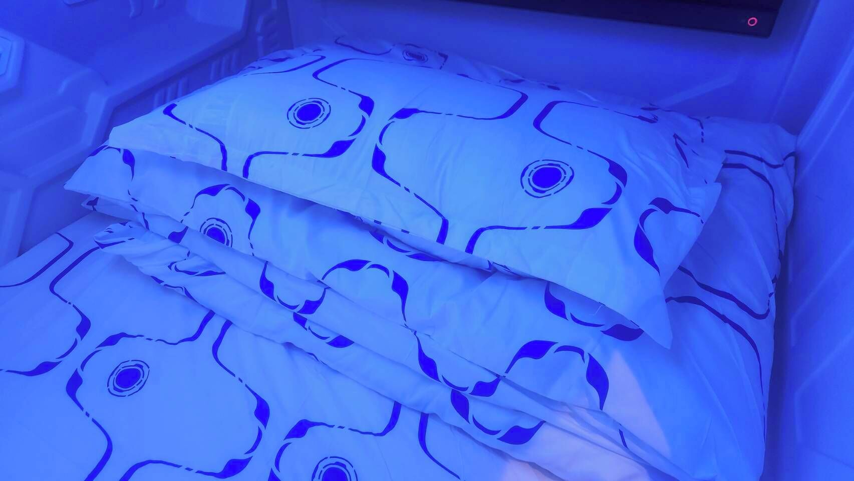 A bed with a blue and white patterned bedspread and pillows.