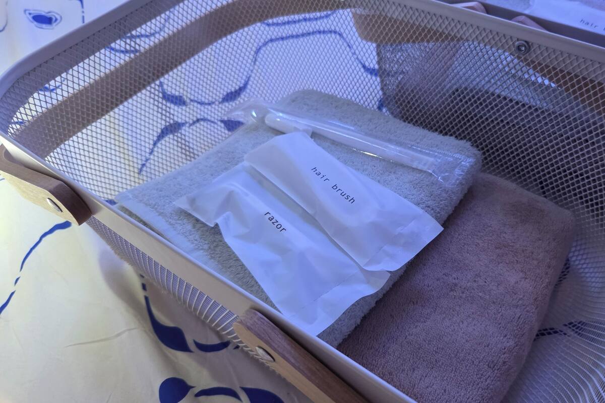 Un panier en filet contenant une brosse à cheveux et un rasoir, posé sur une surface recouverte d’un tissu à motifs.
