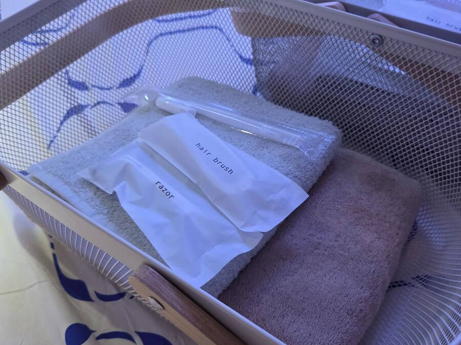 A mesh basket containing a hair brush and a razor, placed on a surface with a patterned cloth.
