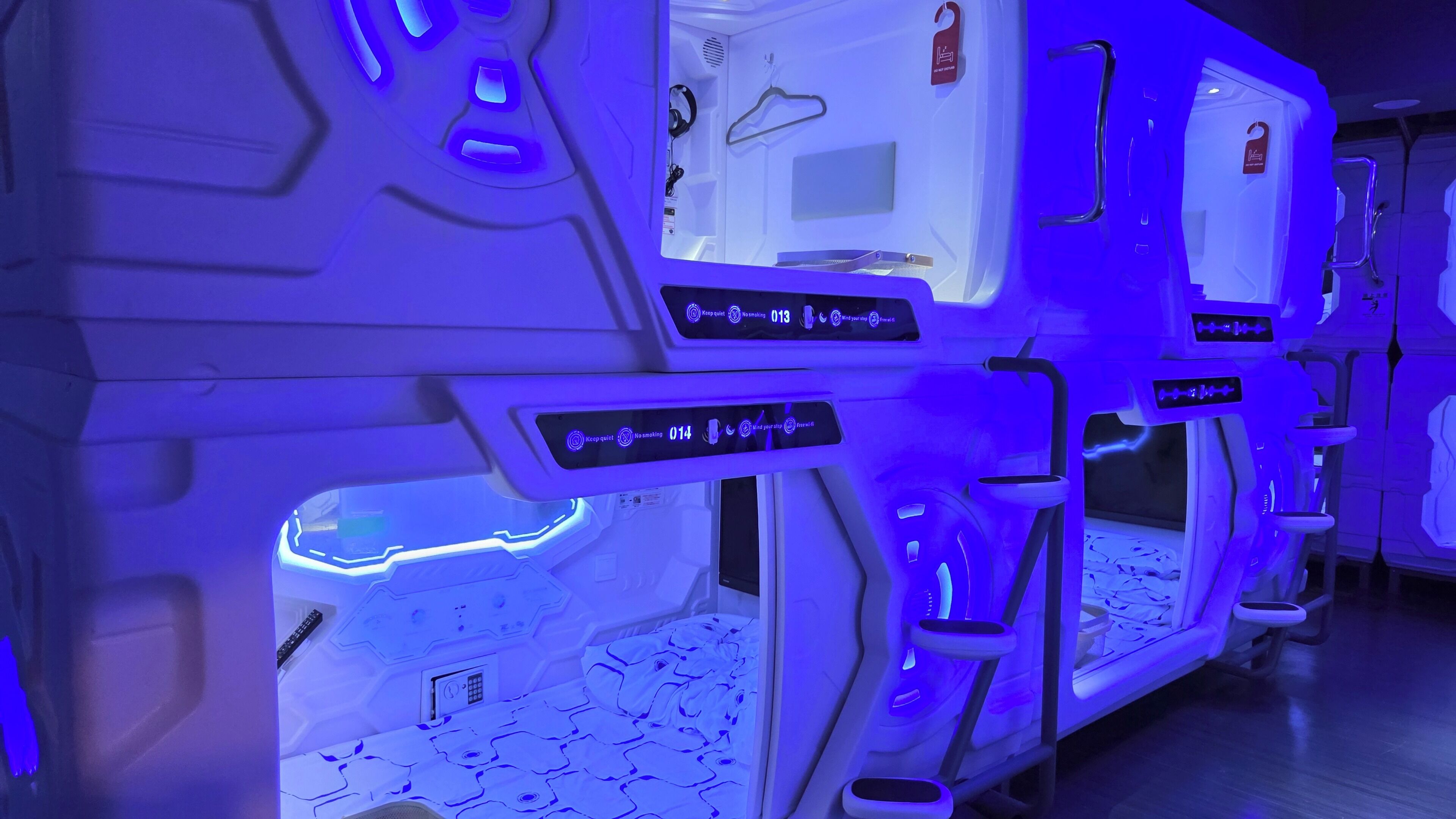 A futuristic room with a control panel, a bed, and a small table.