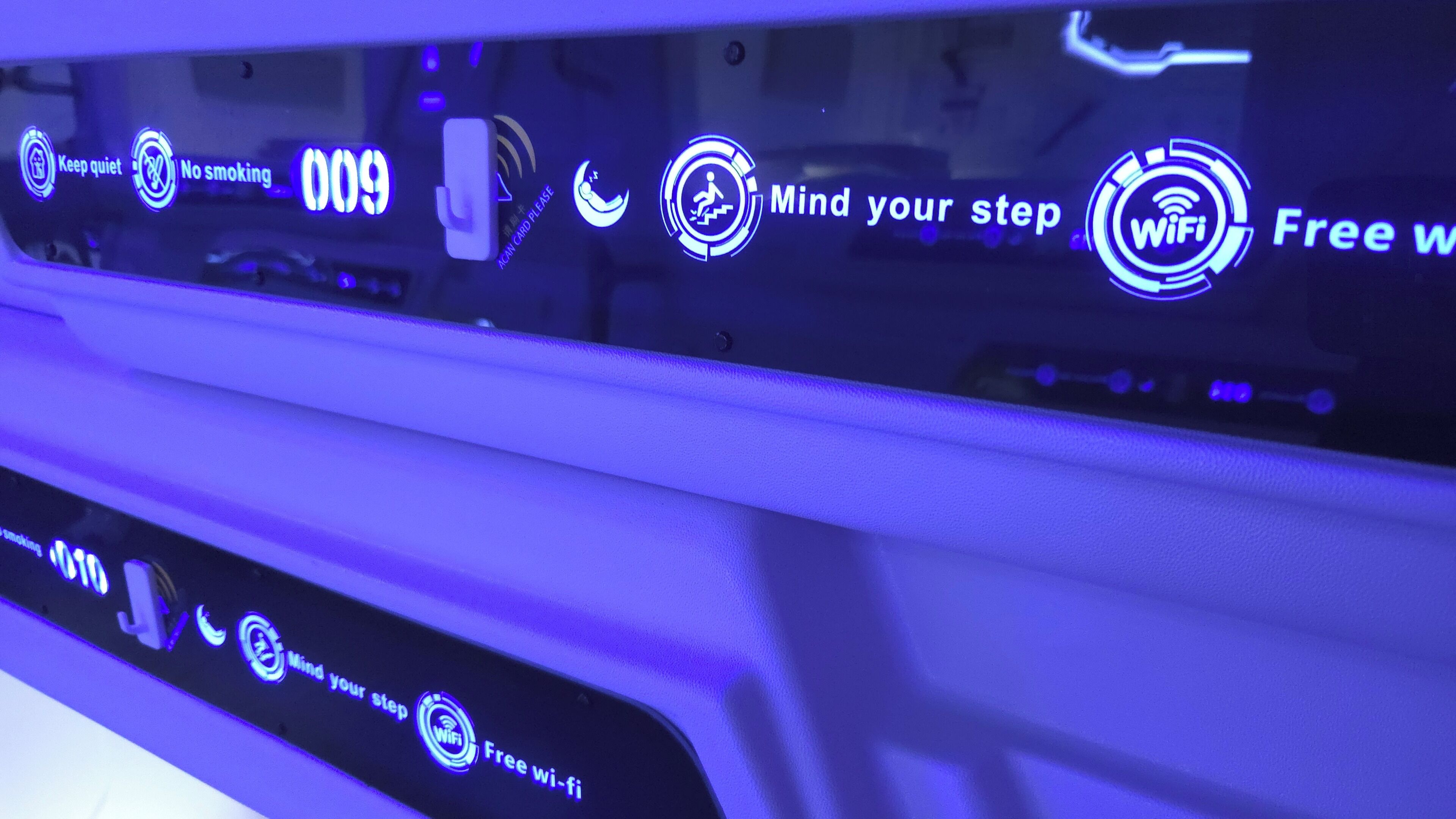 A car's interior with illuminated signs indicating 'Keep quiet,' 'No smoking,' and 'Mind your step.'