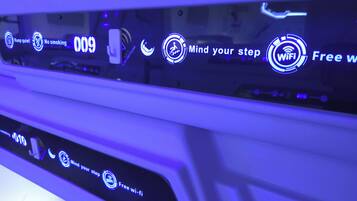 A car's interior with illuminated signs indicating 'Keep quiet,' 'No smoking,' and 'Mind your step.'