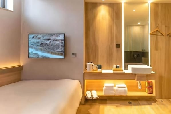 A hotel room with a bed, a mounted TV, a wooden vanity with a sink, and a mirror. - Starway Hotel (Wutai Mountain) (Wutai)