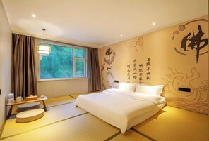 Una habitación con suelo de tatami, una cama, un ventanal con cortinas, una mesita de noche con lámpara y decoración mural.