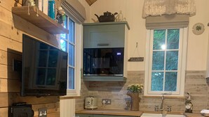 Una cucina rustica con pareti in legno, zoccolo in pietra e tavolo da pranzo in legno.