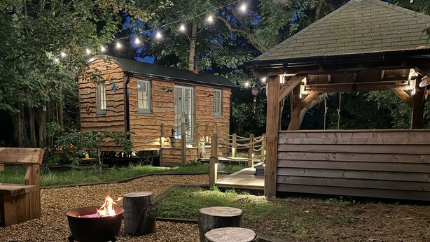 Un rifugio rustico con un braciere, un patio in legno e luci decorative.