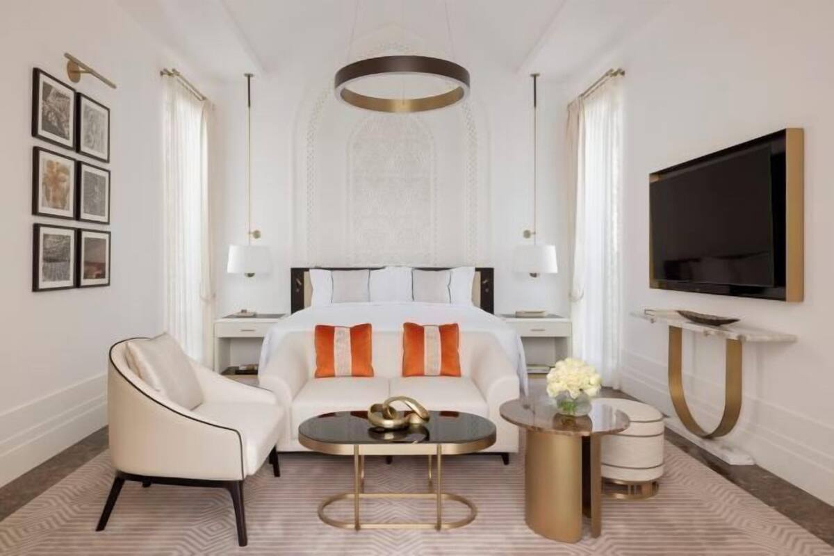 A hotel room with a bed, a sofa, a coffee table, a TV, and framed pictures on the wall.