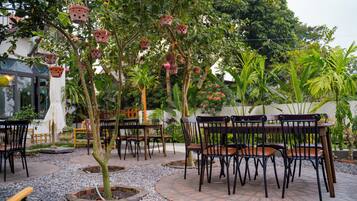 An outdoor seating area with tables and chairs, surrounded by trees and plants.