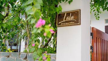 Uma placa de madeira com o nome 'Lala Boutique Village' numa parede branca.