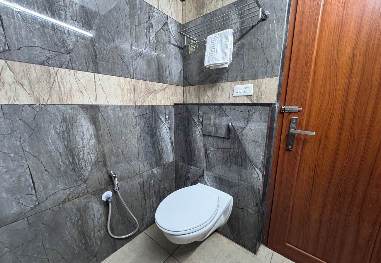 A bathroom with a toilet, shower, and a towel rack.