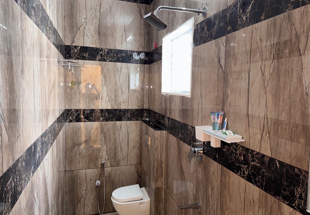 Ein Badezimmer mit Dusche, Toilette und einem Ablagefach für Toilettenartikel.