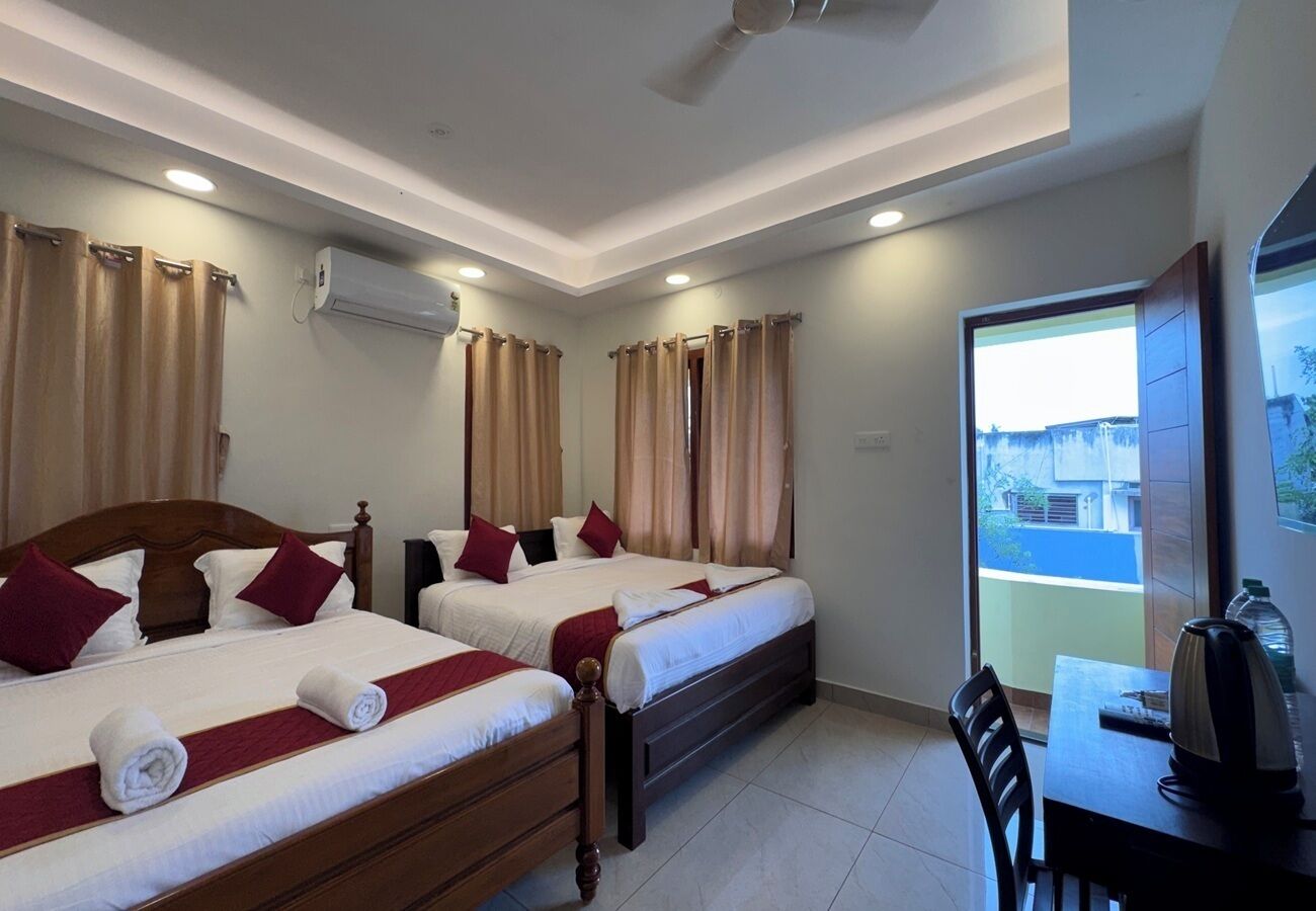 A hotel room with two beds, a desk, and a view of the outside.