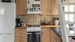 Eine Küche mit Kühlschrank, Mikrowelle, Herd und Holzschränken.