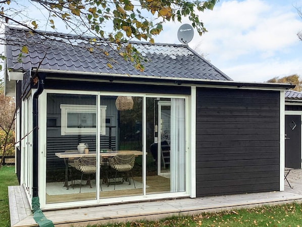 A modern house with a large sliding glass door, a deck, and a satellite dish.