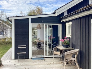 A covered outdoor area with a table and chairs, a bench, and a door leading to a glass door.