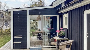 Ein Haus mit Terrasse, einer Schiebetür, Korbmöbeln und einem Blumentopf.