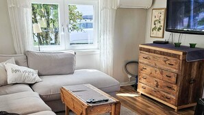Ein Wohnzimmer mit einer Couch, einem Holztisch, einem Fernseher und einer Holzkommode.