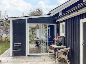 A house with a deck, a sliding glass door, wicker furniture, and a potted plant.