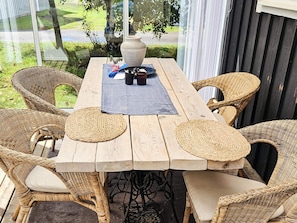A wooden table with woven chairs, a vase, and a placemat.