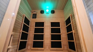 Un sauna avec des parois en bois, un panneau de commande et deux haut-parleurs.