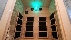 A sauna room with wooden slats, a control panel, and two speakers. - Pool | Spa | Sauna | Fire pit | Cold Plunge (Yucca Valley)