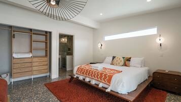 Une chambre à coucher moderne avec un lit, un banc en bois, un tapis rouge et un dressing.