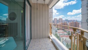 A balcony with a tiled floor, a glass door, and a view of a cityscape.