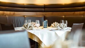 En restaurang med avskilda sittplatser i bås, vita dukar och vikta servetter.
