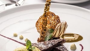 En desserttallrik med olika sorters mat, inklusive en bit choklad, en frukt och en klick grädde.
