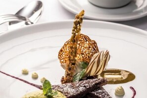 A dessert plate with a variety of food items, including a chocolate piece, a fruit, and a dollop of cream. - Hotel Sternen Oerlikon (Zurich)