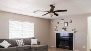 A living room with a sectional sofa, a fireplace, and a ceiling fan. - Casa Sol, centrally located in Bullhead City, Az (Bullhead City)