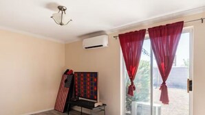A room with a wooden floor, a bed with patterned bedding, a small table with a board game, and a sliding glass door with red curtains. - Casa Sol, centrally located in Bullhead City, Az (Bullhead City)