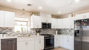 A modern kitchen with white cabinets, a stainless steel refrigerator, a microwave, and a stove. - Casa Sol, centrally located in Bullhead City, Az (Bullhead City)