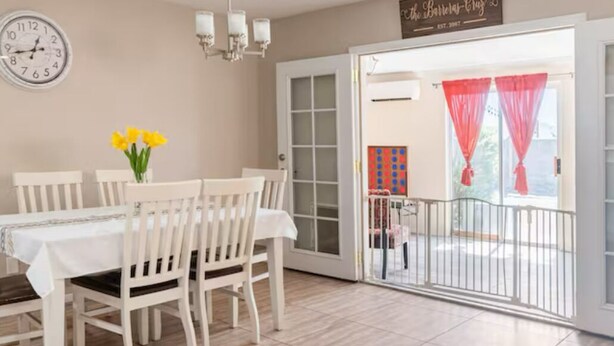 A dining area with a white table and chairs, a wall clock, and a chandelier. - Casa Sol, centrally located in Bullhead City, Az (Bullhead City)