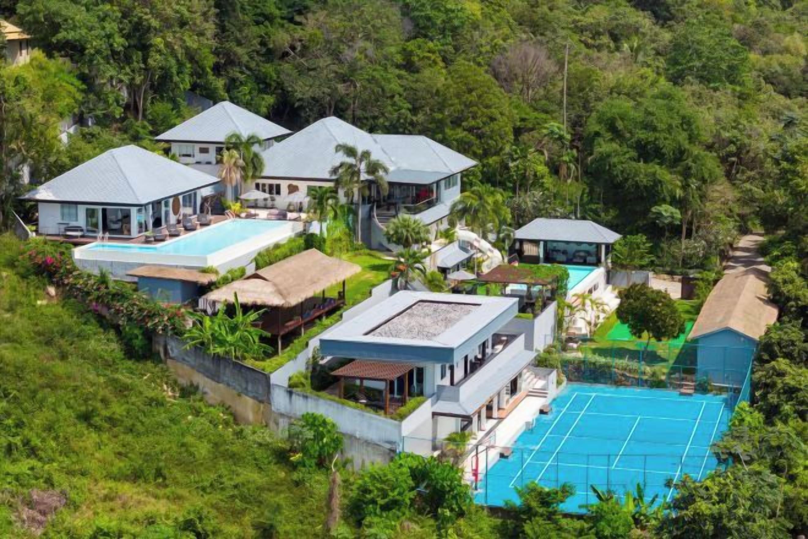 A resort with multiple buildings, including a large swimming pool and a tennis court.