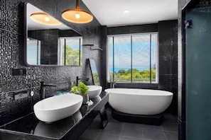 Un bagno moderno con una vasca da bagno ampia, due lavandini, uno specchio grande e vista sul verde dalla finestra.