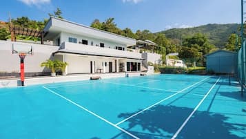 A modern building with a basketball court, a tennis court, and a pool.
