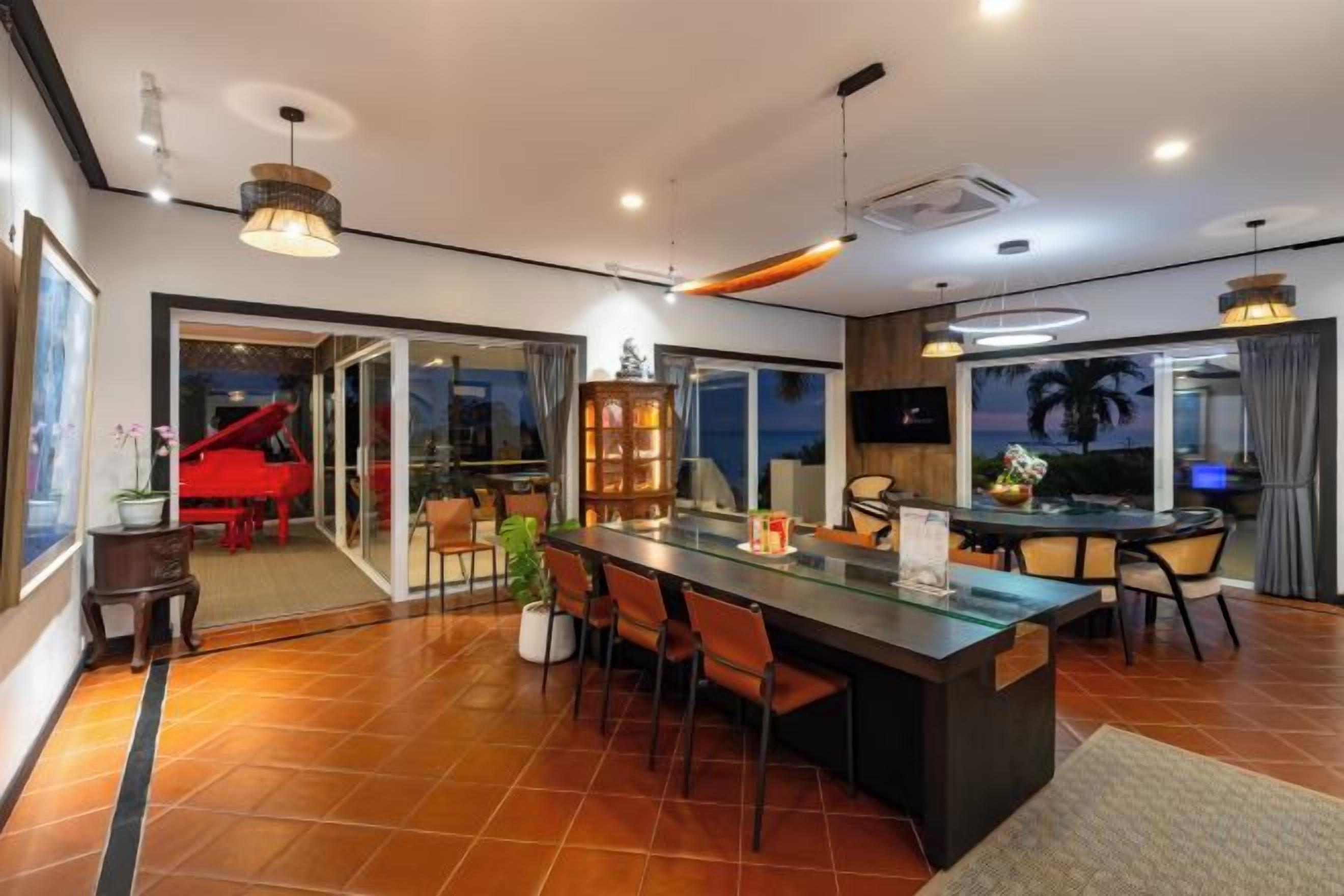A modern kitchen with a central island, dining area, and a piano.