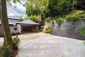 Propiedad residencial con entrada pavimentada, un garaje cubierto y un muro de piedra.